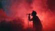 © mila103 - Silhouette of male singer performing in red backlit smoke on stage.
