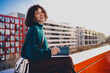 © BullRun - Freelancer looks over shoulder smiling, holding stylus and tablet on red wall, evoking confidence, freedom and ease of remote creative work powered by everyday mobile technology.