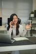 © Prathankarnpap - Photo a beautiful woman using a smartphone to calling someone while sitting in front a computer