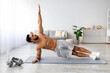 © Prostock-studio - Handsome young Arab man standing in side plank on yoga mat at home, copy space. Millennial Eastern guy exercising core muscles, doing strength workout, leading active lifestyle indoors