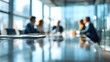 © sharepop - Blurred business meeting around a reflective conference table indoors.