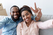 © Prostock-studio - Smiling young black couple rest on couch, man shows peace sign, makes selfie in room with cardboard boxes celebrating moving. First time at home, buyers, renters, owners have fun, enjoy relocation