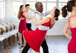 © JackF - Energy African American man and Asian woman are dancing classic version of waltz in couple during lesson at studio. Leisure activities and physical activity for positive people.