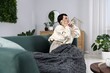 © New Africa - Woman talking over phone on sofa at home