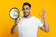 © Prostock-studio - Excited arab guy speaking loud and raising hand up, using megaphone on yellow studio background. Happy middle-eastern man give announcement or advertising, using loudspeaker, closeup