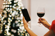 © Prostock-studio - Online Date, Safe Meeting With Friends. Over The Shoulder Back View Of Young Woman Looking At Phone With Blank Mock Up Screen Talking By Video Chat Using Cell Phone, Drinking Red Wine Holding Glass