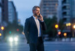 © be free - Business communication of businessman at night. Business man talking on phone outdoor. Businessman negotiation online. Man phone conversation in suit. Mature Hispanic business man with phone