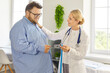 © Studio Romantic - Female doctor and fat overweight patient in health consultation. Clinician holds a tape, discussing waist measurement, weight goals, and obesity risks in medical clinic. Medicine concept.