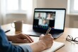© Andrey - Man hand writing in notebook while attending virtual video call on laptop. Online learning or remote work concept for conference or webinar.