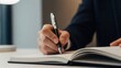 © vadosloginov - Person writing in notebook with pen