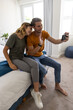 © wavebreak3 - Couple sitting closely on bright bed edge at home viewing smartphone with test stick