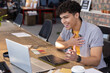 © wavebreak3 - African american man working on laptop and graphics tablet at shared wooden desk