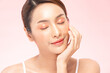 © 220 Selfmade studio - Beautiful asian woman touching smooth face with closed eyes showing clean glowing skin skincare beauty concept posing against pink background looking peaceful relaxed calm satisfied and happy