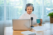 © wirojsid - Happy retired Asian senior woman enjoying a peaceful home lifestyle with podcasting, coffee, and digital freedom