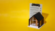 © จุฑารัตน์ เจริญวงษ์ - Small house model and completed inspection checklist document on yellow background.