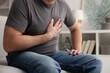 © New Africa - Heart attack. Man suffering from pain in chest indoors, closeup