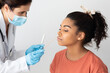 © Prostock-studio - Coronavirus, COVID-19 pcr test concept. Doctor taking nasal swab for coronavirus sample test from potentially infected female patient african american woman at hospital, studio background, closeup