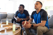 © Wavebreak Media - Diverse male friends in matching shirts watching game at home holding football pizza, copy space