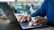© MDRatul - Person typing on laptop with tax icons and hologram