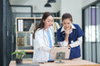 © Thitisak - Two female healthcare workers, one in blue scrubs and another in a white lab coat, are collaborating and reviewing patient charts on a clipboard and tablet. They are engaged in a professional discussi