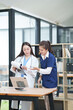 © Thitisak - Two female healthcare workers, one in blue scrubs and another in a white lab coat, are collaborating and reviewing patient charts on a clipboard and tablet. They are engaged in a professional discussi