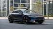 © TAMA - A sleek blue car drives down a city street with modern buildings and greenery in the background