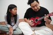 © airdone - Asian father teaching his young daughter how to play the ukulele at home