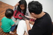 © airdone - Asian father teaching his young daughter how to play the ukulele at home