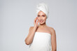 © fotofabrika - Woman poses after shower in white towel with light background in a simple setting