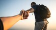 © alvi - A man with a backpack holds hands with someone out of frame against a sunset or sunrise sky.