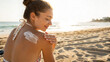 © Hanna - Woman applying sunscreen on her shoulder while sitting on a beach at sunset near the ocean