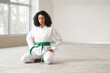 © Pixel-Shot - Young African-American woman with green belt practicing karate in dojo