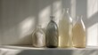 © Vitalii - Four glass bottles of different sizes and shapes arranged on a white surface. the bottles are arranged in a row, with the largest one in the center and two smaller ones on either side.