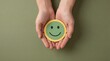 © Bilal - Person holding a green smiley face with a yellow border in their cupped hands, conveying a sense of happiness and positivity with a simple gesture