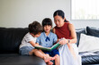 © NZstockphoto - Two children engage with their mother while reading a book together in a bright room