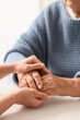 © Pixel-Shot - Senior woman with daughter holding hands at table, closeup