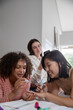 © wavebreak3 - Diverse female friends on bed at home using manicure tools and snapping photos with smartphone