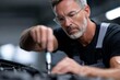 © Yevheniia - Mature caucasian male mechanic fixing engine with focus and precision