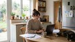 © PureVisualsFrame - Cozy home office scene with a smiling woman working on a laptop at a wooden kitchen table surrounded by papers, mug, plants, and a relaxed cat nearby in a bright, inviting kitchen