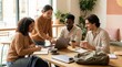 © PureVisualsFrame - Four diverse professionals collaborate around a sunlit wooden table in a modern office, sharing ideas, taking notes, and working on laptops during a casual brainstorming session for a collaborative at
