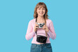 © Pixel-Shot - Beautiful young woman with camera and bag on blue background
