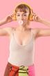 © Pixel-Shot - Beautiful young woman with headphones and chewing gum on pink background