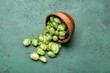 © Pixel-Shot - Wooden bowl with fresh green hops on color background