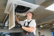 © Serhii - Hvac technician servicing ceiling air conditioning unit filter