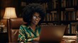 © ArtMajestic - Black woman psychologist with afro hair and glasses smiling while typing on laptop in office with bookshelves. Online consultation and remote therapy session