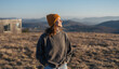 © olezzo - Happy woman in sweater and hat near cabin with hills, eco lifestyle concept