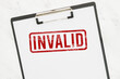 © Reza - Red Invalid rubber stamp on white paper clipboard.