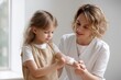 © Anna Lurye - A gentle and focused moment where a female caregiver, wearing a clean white tunic, is carefully cleaning a small injury on a young girl's forearm using a white antiseptic wipe