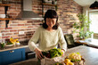 © Davor - Smiling woman unpacking fresh groceries in home kitchen