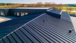 © LIPO@SEXTAO22 - Modern dark metal standing seam roof on a contemporary building, showcasing sleek design and durability against a clear sky. Architecture, Roofing